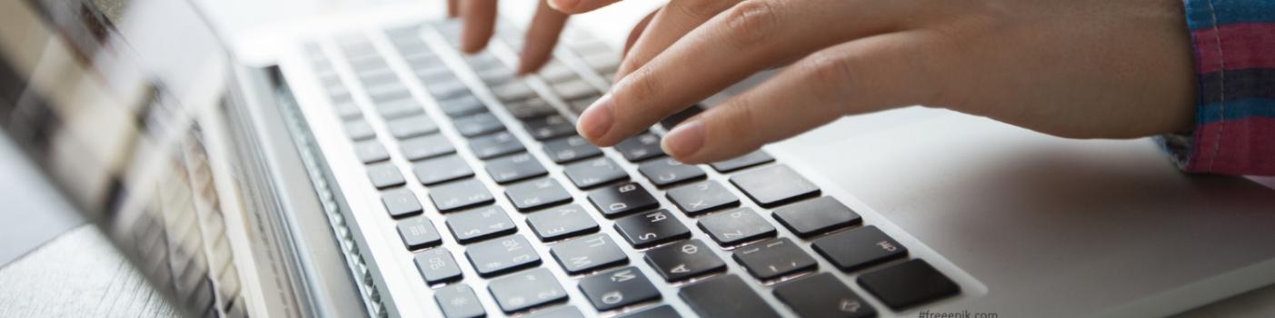 Młode dłonie w bliskim planie nad klawiaturą laptopa