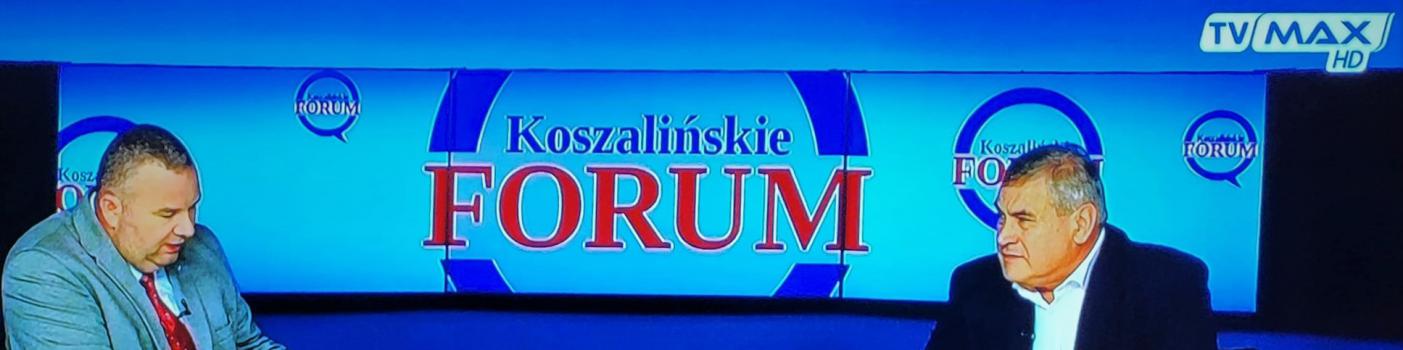 Dwaj mężczyźni w marynarkach siedzą przy zaokrąglonym stole, w tle napis Koszalińskie Forum